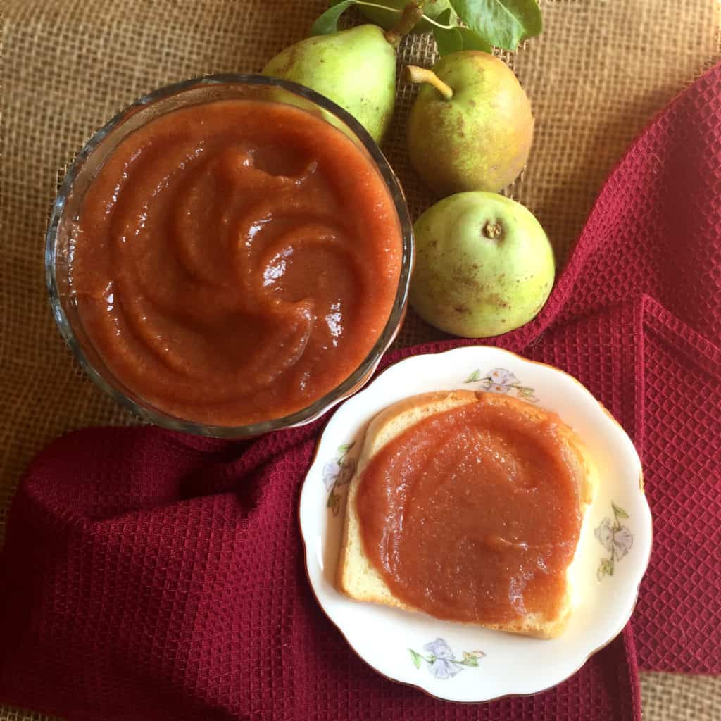 pear butter in a bowl next to a piece of bread with pear butter on it