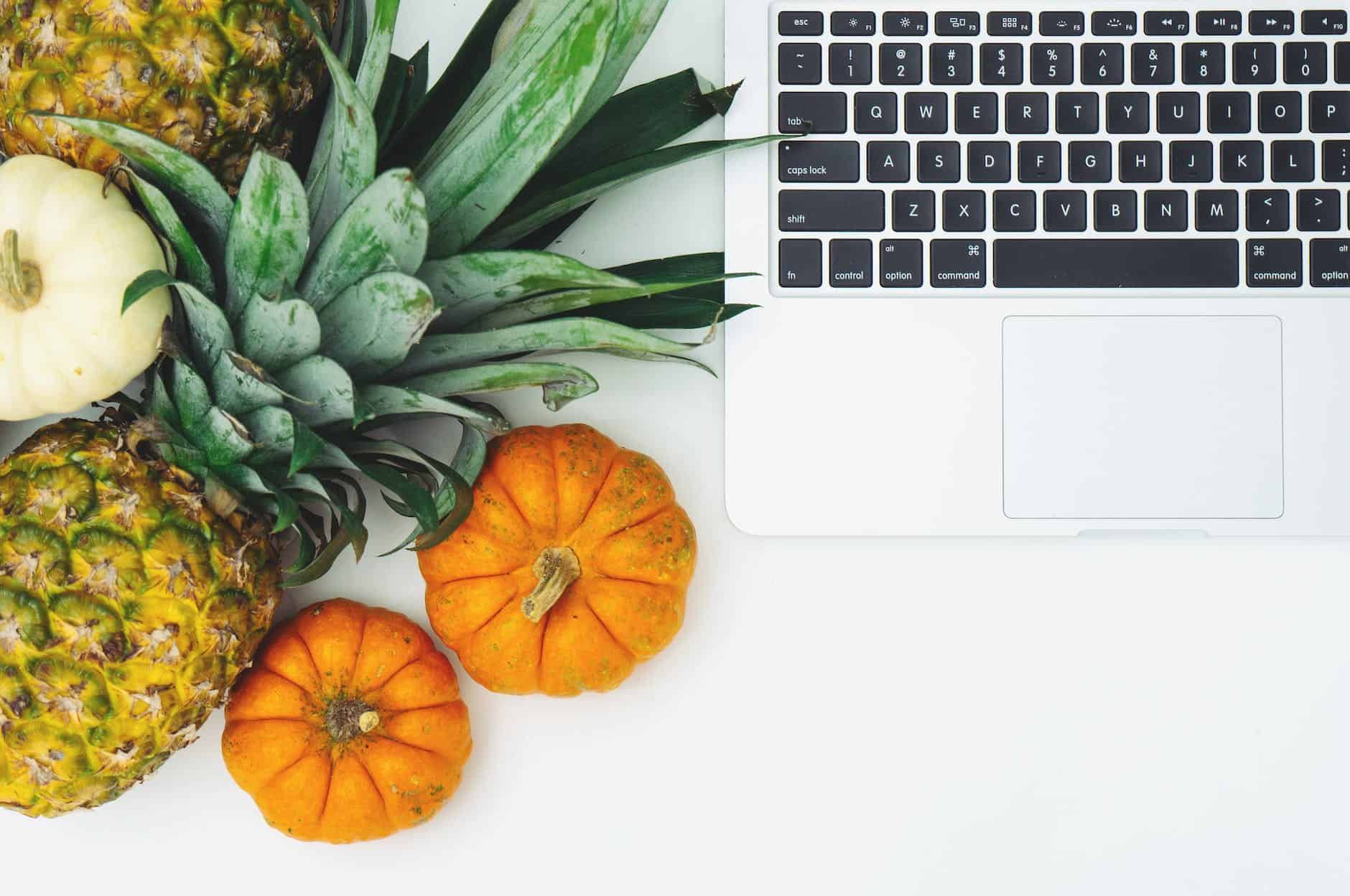 pumpkins and pineapple next to laptop