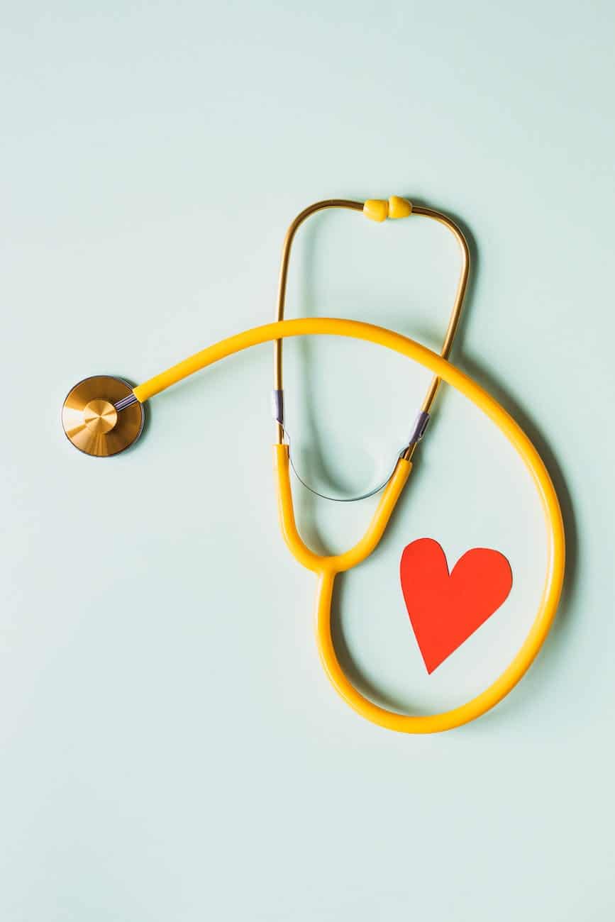 medical stethoscope with red paper heart on white surface