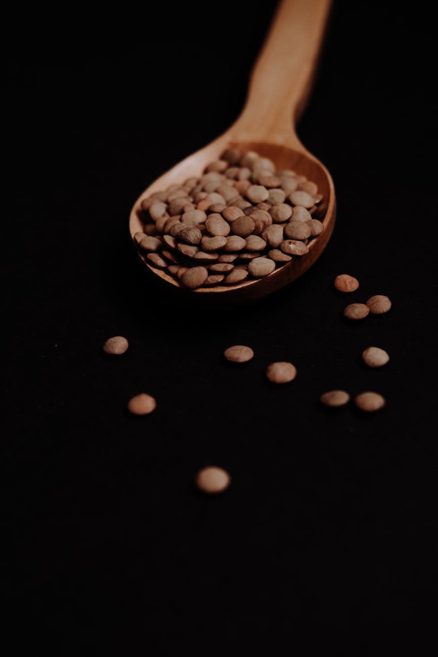 wooden spoon with lentils on black background